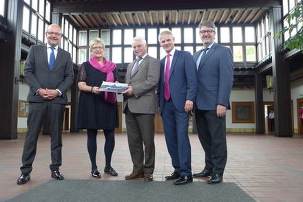 Vertreter der Stadt, vom Land und der Hochschule zeigen den Vertrag.